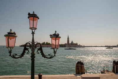 Old streetlight on the bank of a venetian canal with st george major's island on the horizon, venice