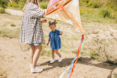 A charming little girl has fun and launches a kite together with her older sister