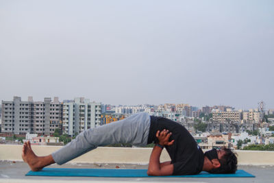 Rear view of man skateboarding on city against sky