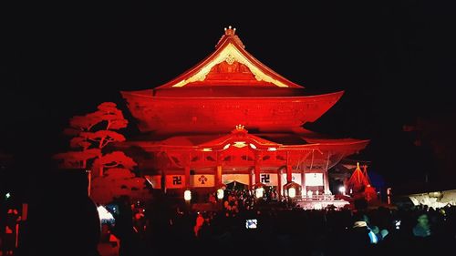 People in illuminated traditional building against sky at night