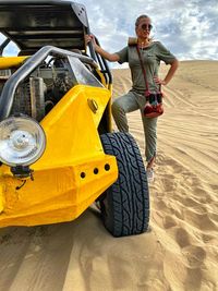 Woman standing by vehicle at desert