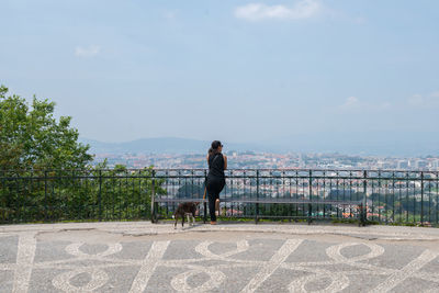 Woman with dog against sky