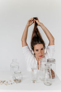 Portrait of smiling young woman drinking glass against white background