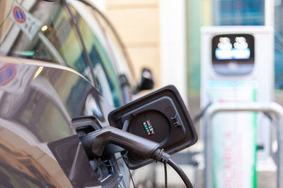 A cable is recharging an electric car at the charging station