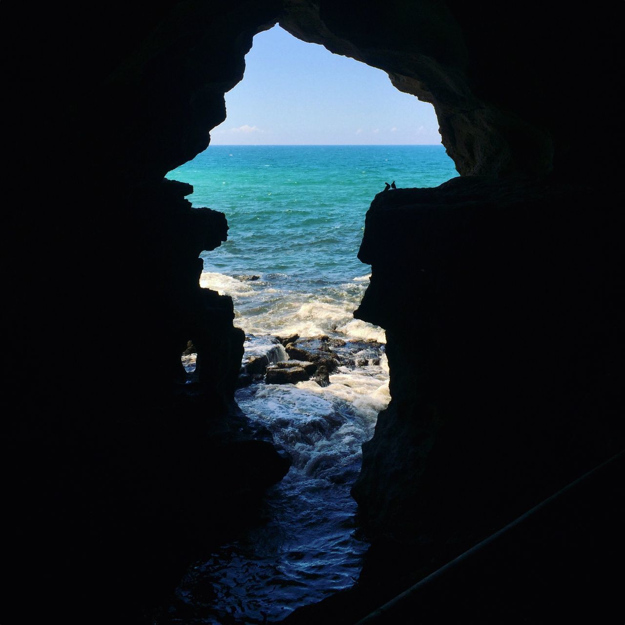 SCENIC VIEW OF SEA AGAINST CLEAR SKY SEEN THROUGH ROCK FORMATION