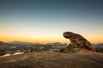 Statue on rock against sky during sunset