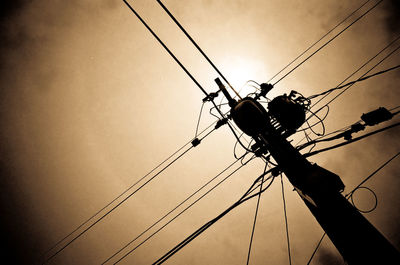 Low angle view of silhouette electricity pylon against sky during sunset