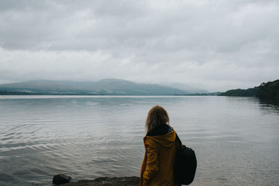 Rear view of woman looking at lake against sky