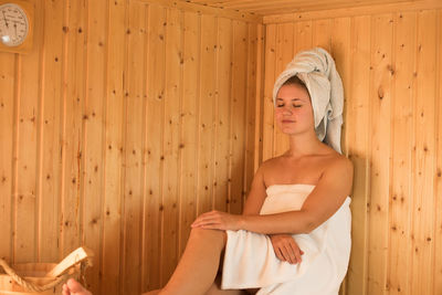 Beautiful young woman relaxing in sauna