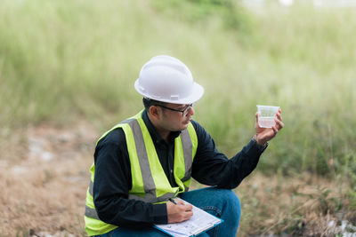 Young woman using mobile phone while sitting on field