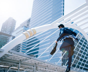 Low angle view of businessman moving on steps against buildings in city