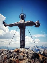 Low angle view of cross sculpture against mountain range