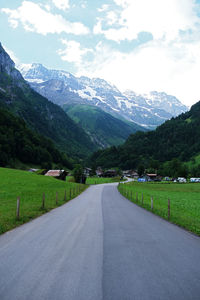 Road leading towards mountains against sky