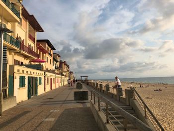 People on beach by buildings against sky