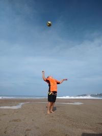 Full length of boy playing with ball at beach against sky