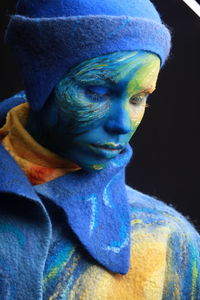 Close-up of young woman with painted face against black background