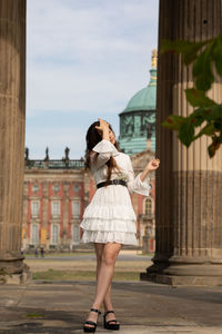 Full length of woman standing by buildings in city