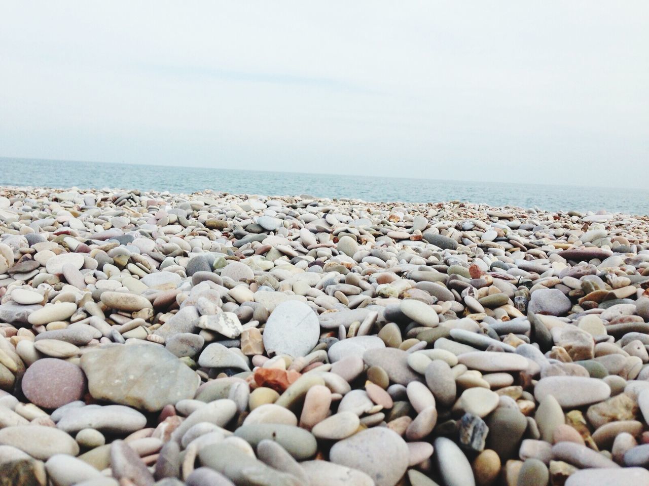 beach, pebble, sea, stone - object, shore, water, horizon over water, abundance, large group of objects, sky, tranquility, rock - object, nature, stone, tranquil scene, scenics, beauty in nature, surface level, day, sand