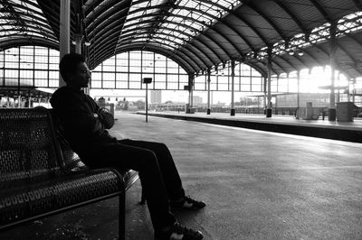 Full length of man on seat at railroad station
