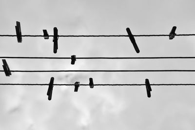 Low angle view of clothespins on rope against the sky