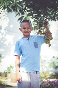 Portrait of boy standing against trees