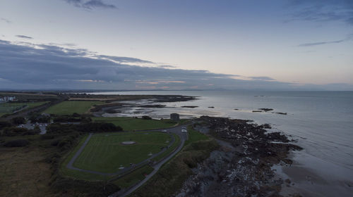 Scenic view of road by sea against sky during sunset