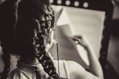 Rear view of girl holding book indoor