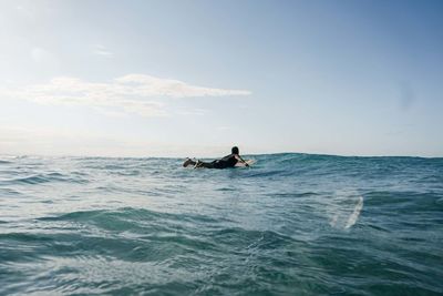 Man surfing in sea against sky