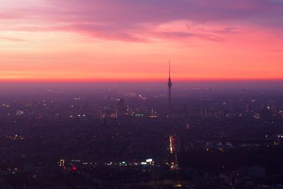 Illuminated buildings in city at sunset