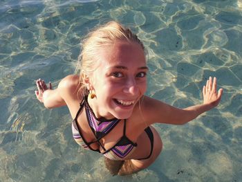 Portrait of happy young woman standing in water at beach 