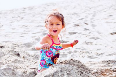 Portrait of happy girl playing on sand at beach