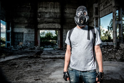 Man wearing gas mask standing under bridge