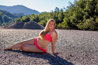 Portrait of woman in bikini sitting on land
