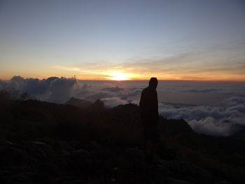 Silhouette man looking at mountains against sky during sunset