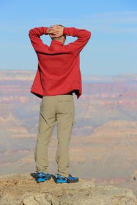 Rear view of man standing on rock at grand canyon national park against sky