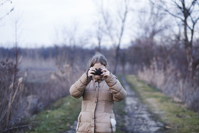 Woman photographing while standing on field