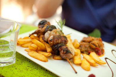 Close-up meat skewer with french fries and ratatouille on table