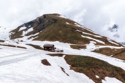 A small hut on top of grindelwald first snow covered summit. mountain and hill tops covered in snow