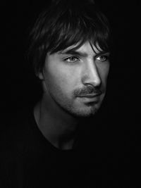 Portrait of young man against black background