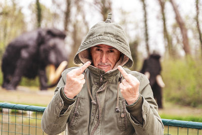 Portrait of expressive middle aged man posing in front of dinosaur models in a public park