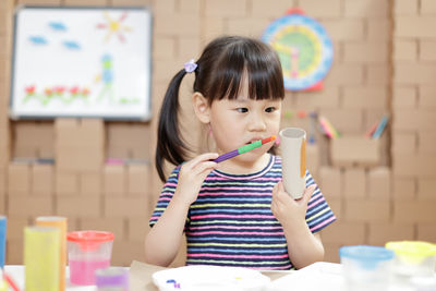 Portrait of cute girl holding table