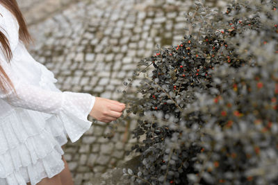 Midsection of woman standing on tree during winter