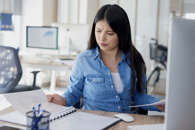 Young woman using mobile phone while sitting on table