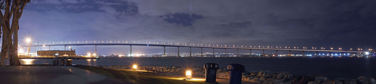 Illuminated bridge over river against sky at night