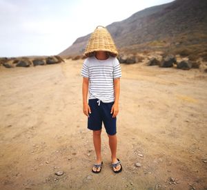 Rear view of boy standing on land against sky