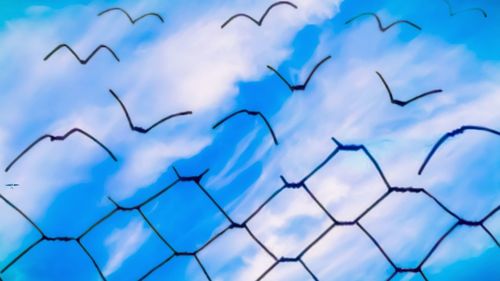 Low angle view of blue sky seen through metal fence