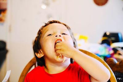 Cute hungry boy eating noodles while sitting at home