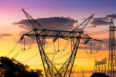 Low angle view of silhouette electricity pylon against sky during sunset