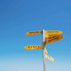 Close-up of road sign against clear blue sky