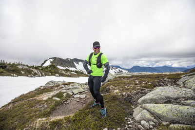 Portrait of trail runner, happily running in the alpine on cloudy day.